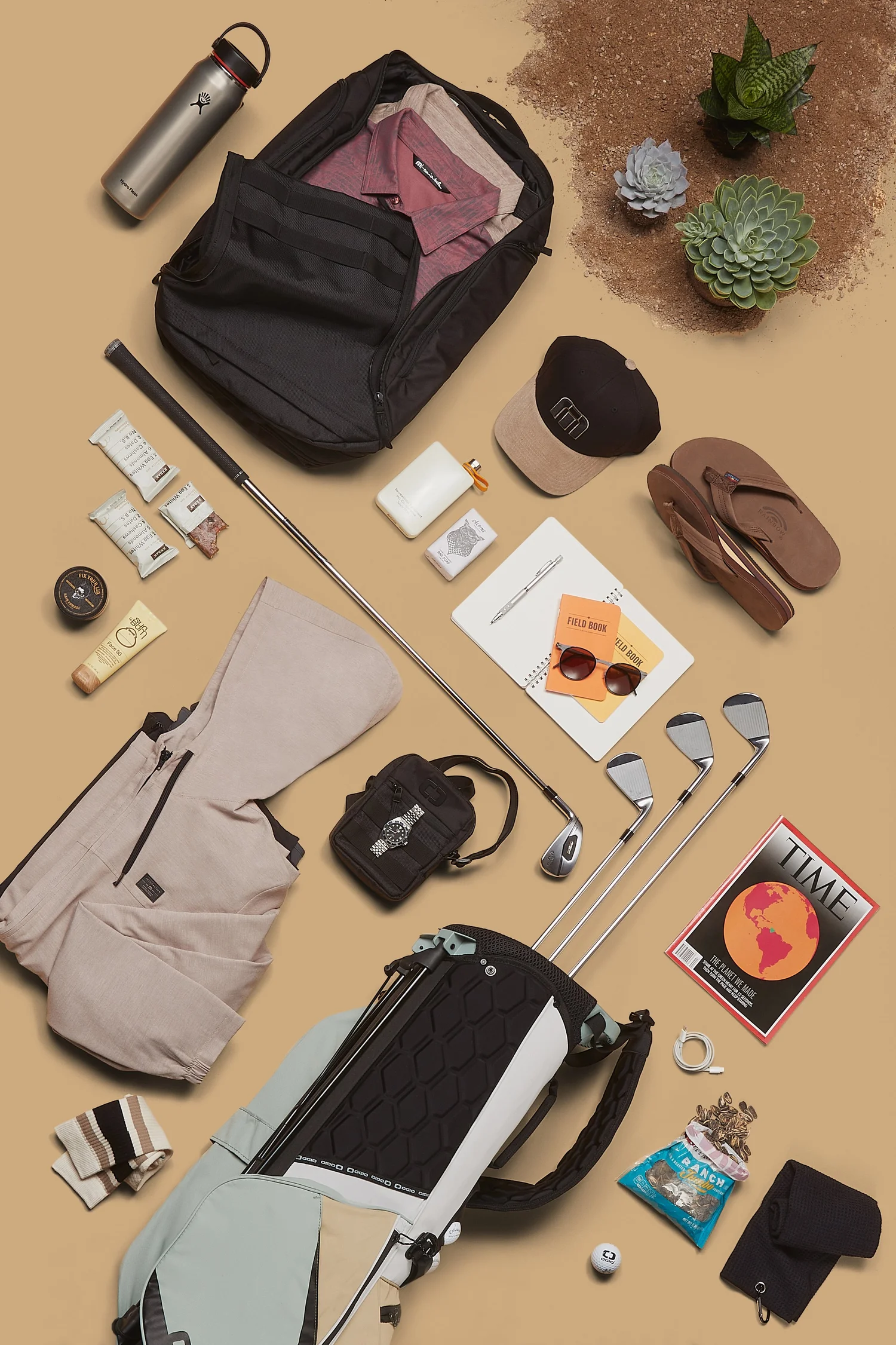 Ogio golf gear flat lay on desert tan
