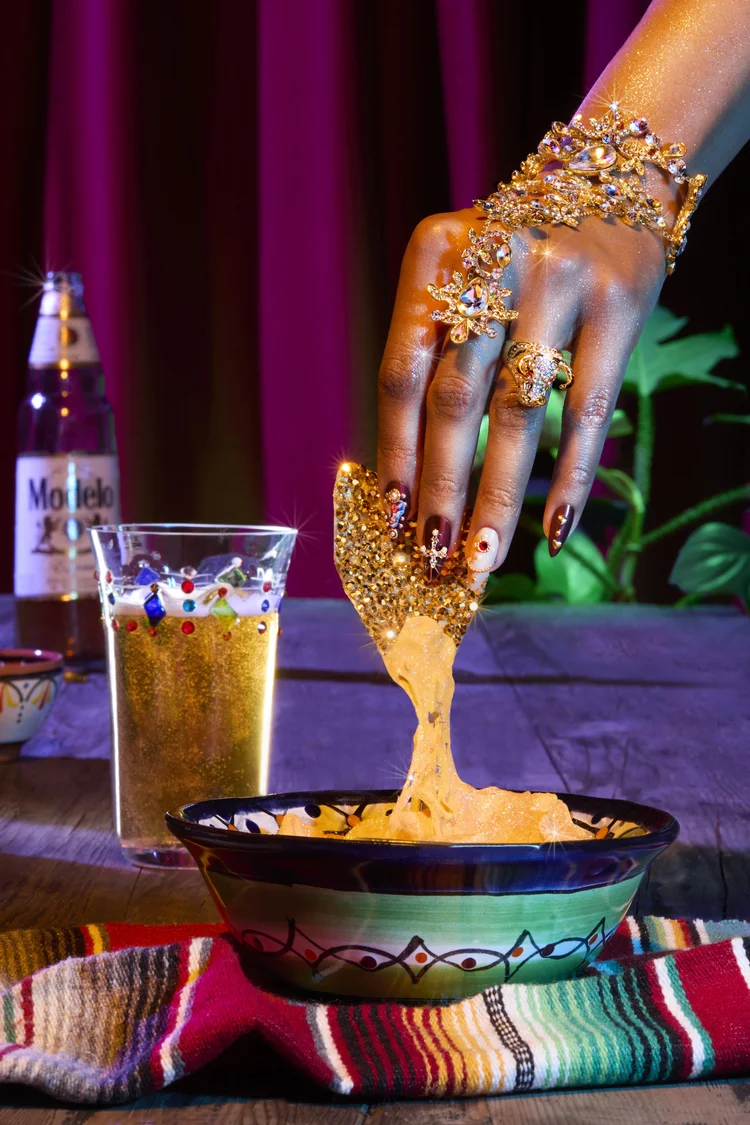 Bedazzled hand dipping into nachos